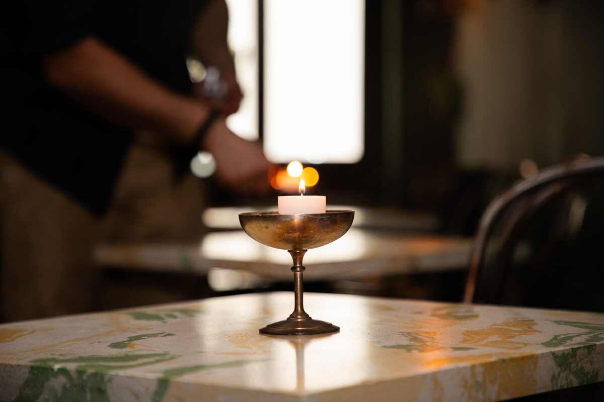 A tealight burning in a brass coupe on a marble table