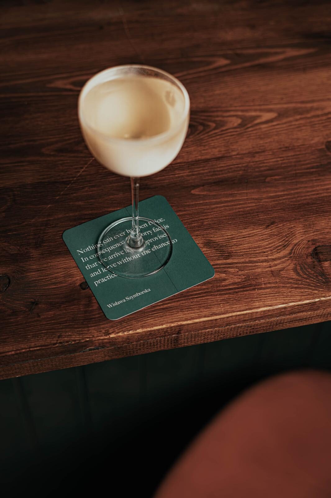 A coupe on a green coaster printed with a line by Wisława Szymborska