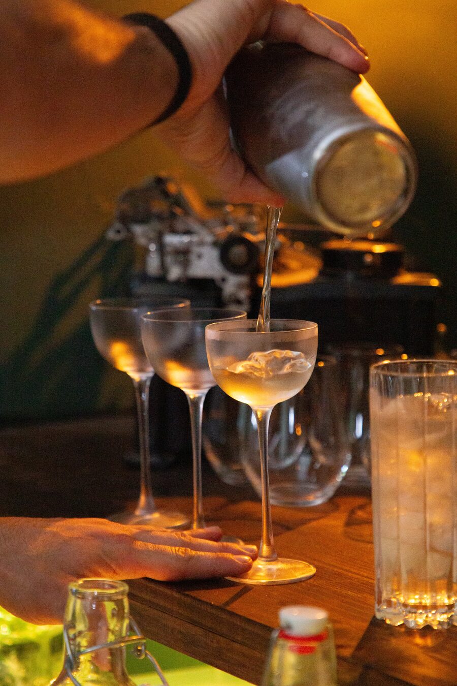 A cocktail poured into a row of frosted glasses at the bar